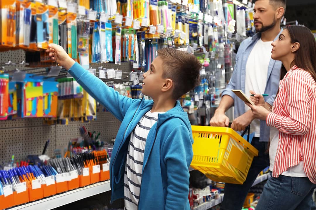 A young boy with his family choosing school supplies in the supermarket.
